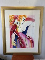 Full view of the framed watercolor painting showing two stylized figures in vibrant colors within a gold frame.