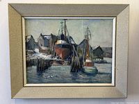 Frontal shot of framed marine oil painting depicting boats and repair yards with buildings in background, artist signed.