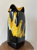 Front and side view of the lava flow blown art glass vase showing yellow and black colors with glossy finish.