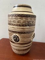 Front view of the vase showing the textured horizontal bands and raised rosettes.