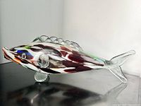 Side angled view of elongated Murano fish glass sculpture showing colorful internal details and textured clear glass fins and tail.