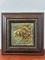 Full front view of square wood frame with bronze relief sculpture depicting a bison.