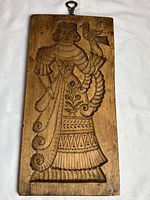 Front side of wooden cookie mold featuring a woman holding a bird.
