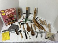 Wide angle photo of all baking accessories included in the lot showing Nordic Ware Krumkake Iron box, wooden rolling pins, and various metal kitchen tools, utensils, and rollers.