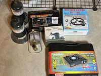 Overview of camping items including fuel canisters, gas stove box, electric pump box, gas burner box, and a gas lantern with stand.