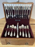 Opened wooden cutlery box showing storage and arrangement of knives, forks, and spoons inside velvet slots