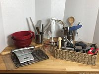 Full view of cooking utensils, mixing bowls, Starfrit digital food scale, measuring cups, and various kitchen tools organized on table including a basket with utensils.