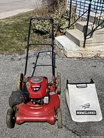 Front view of the Craftsman lawn mower with red deck and detached white dust block bag with Craftsman branding.