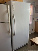Full height view of white upright freezer next to refrigerator in kitchen