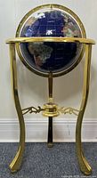 Full front view of lapis lazuli globe mounted on gold-tone brass tripod stand