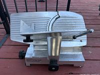 Side view of the Ortega Gravity System meat slicer, showing handle, blade and ribbed sliding platform.