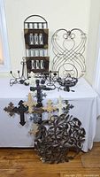 Photo showing the rectangular metal frame with 8 tea light holders and a white metal circular scrollwork piece, plus assorted decorative crosses and floral metal decor