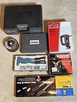 Overview photo of entire tool lot showing all boxed items including Jobmate Cut-Out Tool box, ridgid tool case, grinding discs, riveter, and Husky air hammer box.