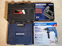Photo shows Mastercraft branded black case, boxed air-powered brad nailer, and blue case for corded hammer drill