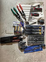 Assorted tools including wood chisels, screwdriver bits, ratchet wrench, socket sets, and circular glass cutter.