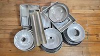 Overview of the lot showing multiple stacked vintage baking pans of various shapes including circular Bundt pans, rectangular loaf pans, and square or rectangular pans.