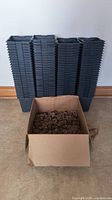 Stack of 106 black plastic 6-inch starter pots with cardboard box of Jiffy Pucks in front.