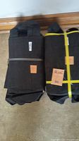 Two bundles of black fabric Root Pouch pots rolled and banded together on floor.