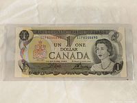 Front side of 1973 Canadian 1 dollar bill showing Queen Elizabeth II portrait, Bank of Canada crest, serial number ECP8344690.