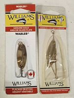 Two sealed Williams Wabler fishing lures with genuine gold and/or silver plating in original packaging.