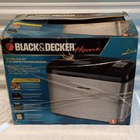 Photo of Black & Decker Ultimate Plus 2 LB Convection Breadmaker in original factory packaging with shrink wrap on box showing product image and branding.
