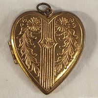Closed heart shaped locket showing floral and striped embossed design on front surface.