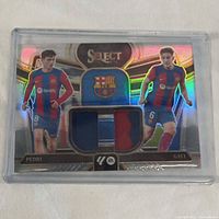 Panini Select soccer card with Pedri and Gavi in blue and red FC Barcelona kits, holographic gold foiled card with embedded fabric patches.