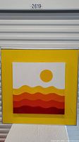 Full view of square painting with abstract yellow, orange and red waves and sun on yellow frame.