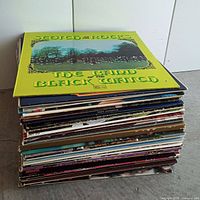 Stack of about 40 vintage vinyl LP records viewed from the side showing colorful album covers and varying spine designs.