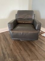 Front view of the black leather armchair showing seat, backrest, and armrests with slight wear on leather.