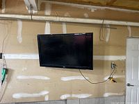 LG 46 inch flat screen television mounted on a wall, showing the front of the TV with screen off, visible power cord plugged into wall outlet.