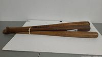 Three wooden baseball bats laid side by side showing overall length and condition.