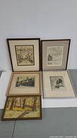 Overview of all five framed artworks showing assorted vintage landscapes, etchings, and paintings.