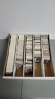 Multiple rows of hockey cards stacked in a white cardboard box, showing thickness and organization of the collection.