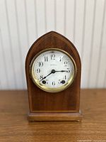 Front view of clock showing the dial with the Seth Thomas branding, brass bezel, and wooden beehive-shaped case.