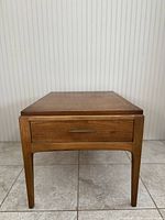 Front view of walnut end table showing drawer and tapered legs