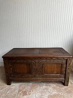 Front view of rectangular wooden chest with carved Renaissance-style motifs and two recessed panels.