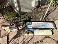 Lot shows the Pro Series Croquet set in its canvas bag along with boxed Leisure Time Hammock and Stansbury Dining Canopy on stone patio outdoors in daylight.