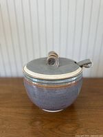 Front side view of the vintage glazed ceramic stoneware ladle pot with lid, showing the full rounded body and ladle handle.