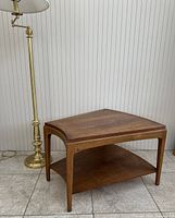 Angled front view showing wedge-shaped top, tapered legs, and lower storage shelf.