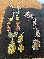 Antique style multicolor resin and metal necklace, matching earrings, and pendant on black background