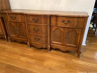 Front view of antique oak sideboard showing metal handles, lattice doors, and curved drawer fronts.