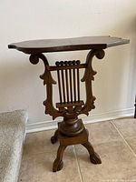 Full side view of antique wooden accent table showing unique shaped top and carved decorative legs.