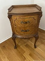 View of the antique wooden side table showing ornate details and claw feet.