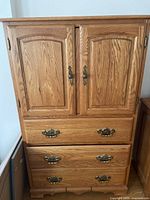 Photo of oak wood cabinet showing two paneled doors with brass handles, three drawers with brass handles, made in Canada by Sharmag.