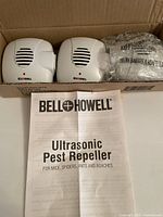 Two Bell + Howell ultrasonic pest repeller devices in their box alongside the user manual.