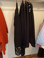 All 6 black women's sweaters and jackets hanging in a row, showing overall color and style variety.