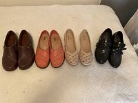 Four pairs of women's shoes laid out side by side showing overall condition and styles in brown, red, beige, and black patent leather.