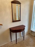 Wide view of the entryway table and mirror set against a wall in an entryway, showing the scale and placement of both pieces.