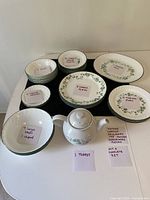 Full set of Corelle Calloway Ivy dinnerware displayed on a table with labeled sticky notes identifying quantities and a note about one chipped bowl.